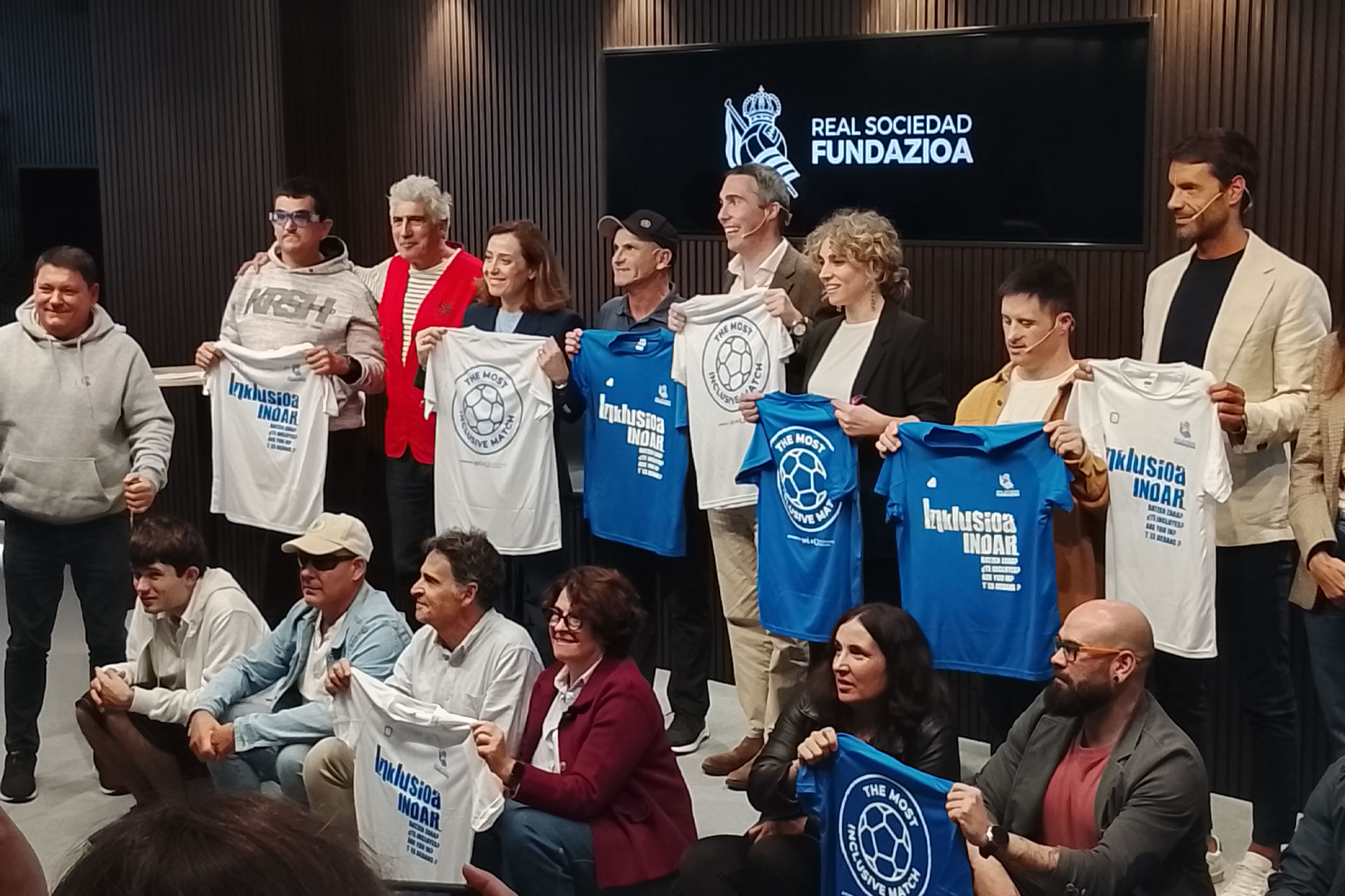 Varias personas posando para al foto sosteniendo una camiseta