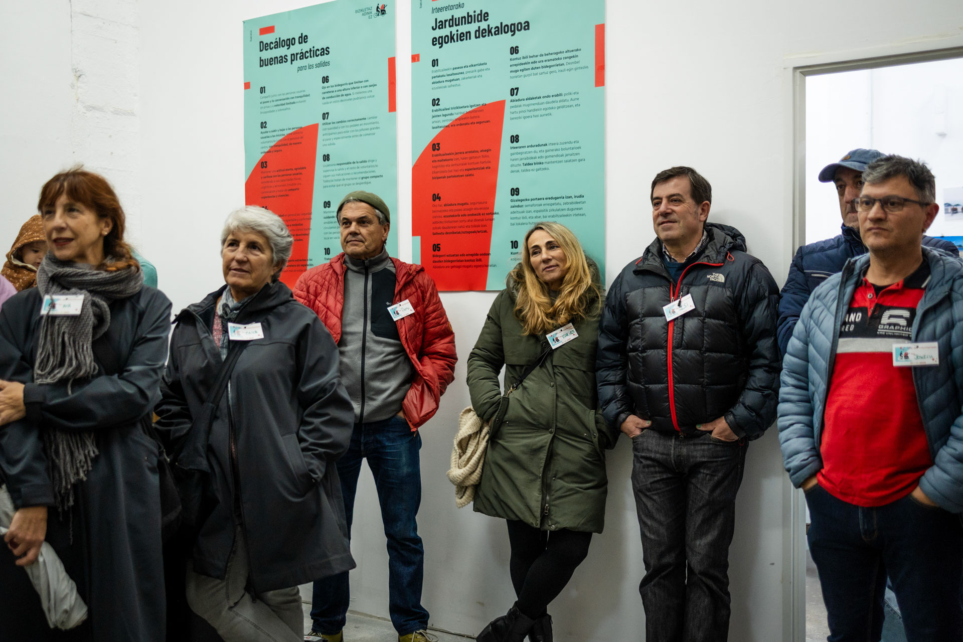 Grupo de personas reunidas en un garaje, con posteres de BAE detrás